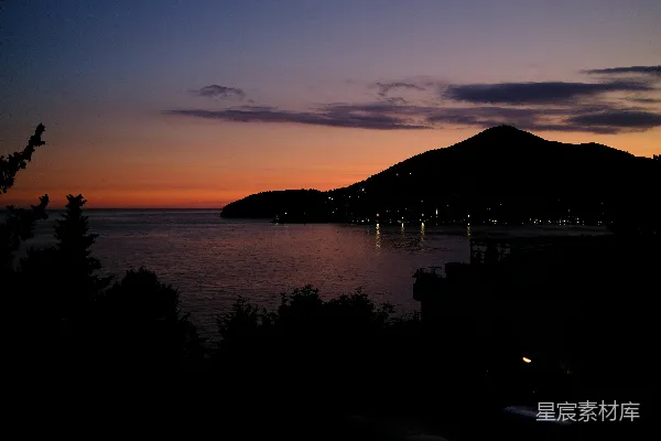 沿海小镇上璀璨的夕阳和暗淡的山峦。
