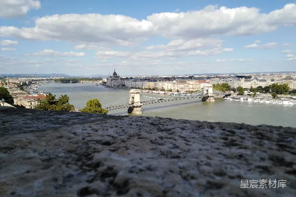 白天高空拍摄的城市高楼大厦、观景桥和海景，背景是白云蓝天的天空