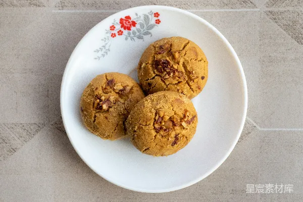 一张白色 plates 上放着三块饼干，放在桌子上。