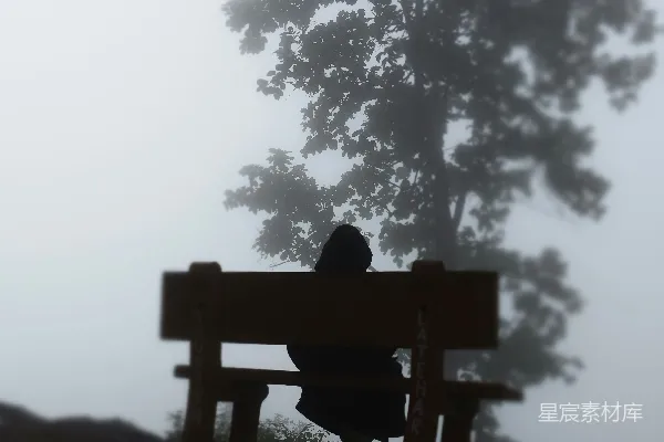 一个人在雾中坐在长椅上。