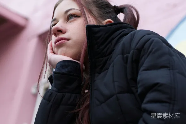一个女人坐在粉红色的墙上。