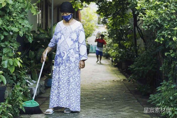 白蓝花卉长袖连衣裙的女人正在拿着绿色的扫帚。