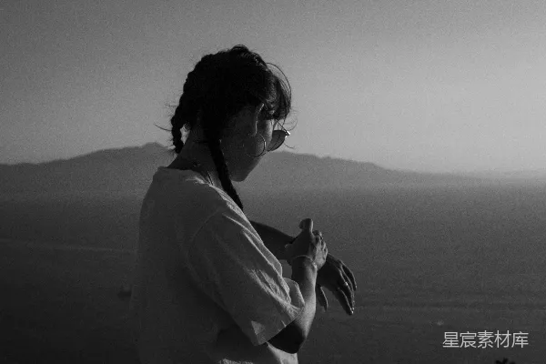 留着辫子的女人低头望着海洋