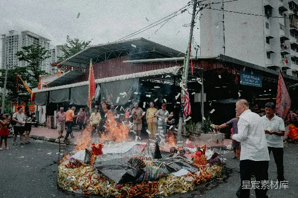 高清摄影 人们在街道上焚烧祭品，旁边有建筑物。