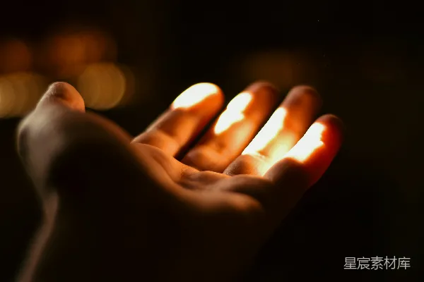 手中握着一支点燃的蜡烛的人