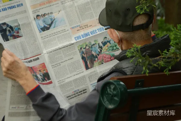 高清摄影 一个男人坐在长椅上读报纸。