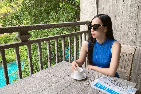 高清摄影 一位女士坐在桌子旁，手里拿着一杯咖啡。