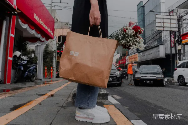 高清摄影 一个人拿着一个棕色的包走在城市街道上