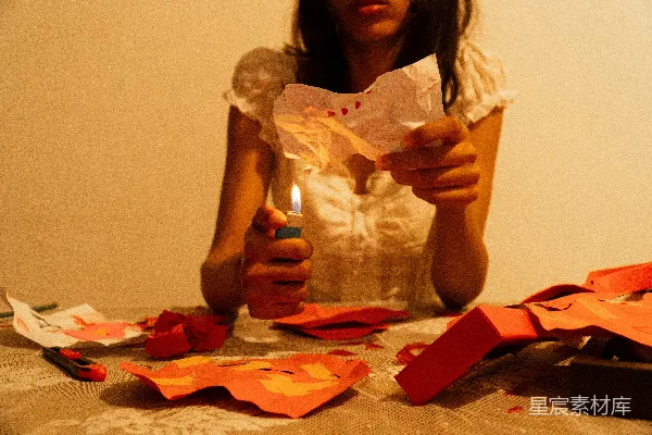 高清摄影 女人在桌子旁用打火机点燃纸张