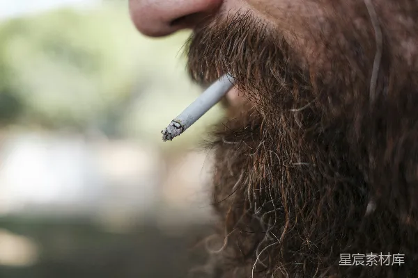 留须男子正在吸烟。