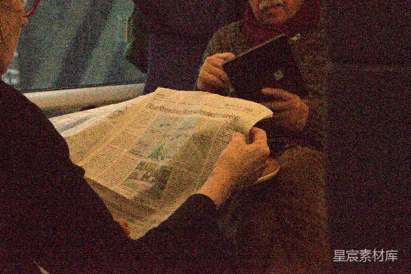 高清摄影 一个人在看报纸，另一个人在用平板电脑。