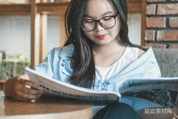 高清摄影 房间里，女人坐在桌子旁边，边读边坐。