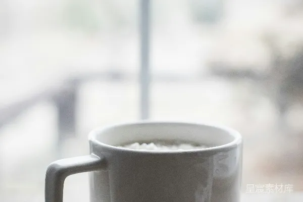 木桌上方放置着一个白色咖啡杯。