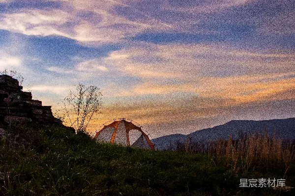 夕阳下白色帐篷置于绿草场上