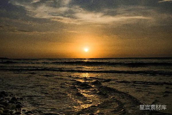 高清摄影 夕阳正在海面上落下，前景中有一些岩石。