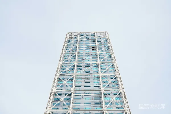 高耸的现代摩天大楼，几何形状的外墙，在晴朗的天空下。