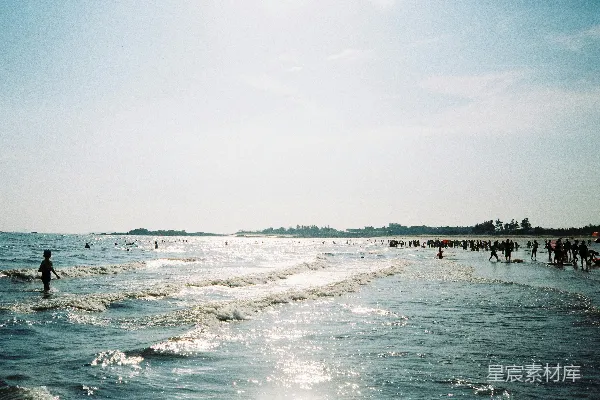 一群人在海滩上站着，旁边是大海。