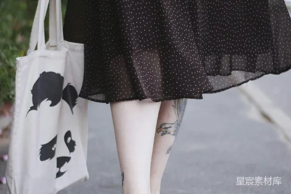身穿黑白条纹上衣的女子手持白色手提包
