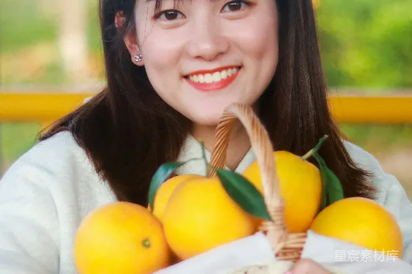 年轻女子手持一篮新鲜的橙子