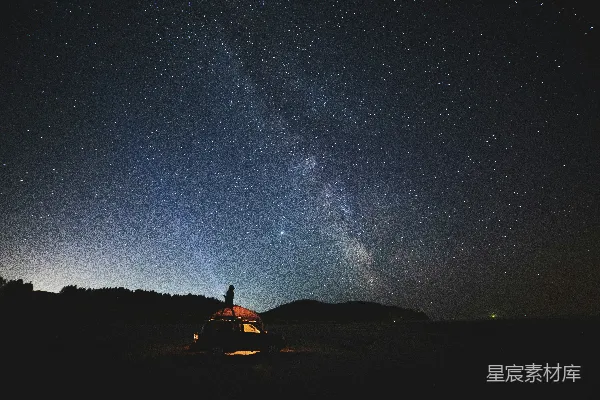 高清摄影 坐在星光闪烁的夜空下的棕色沙地上的人
