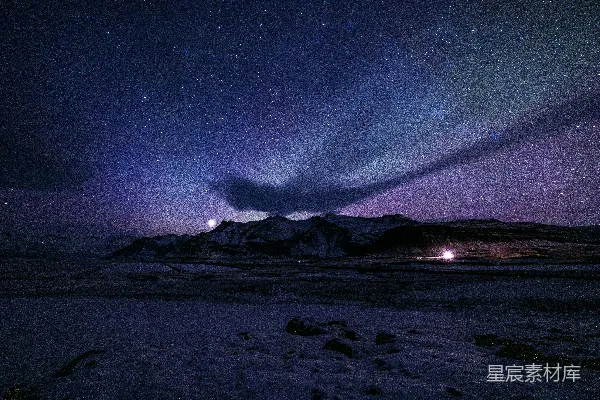 北极光照亮一片繁星满天的雪山之顶。