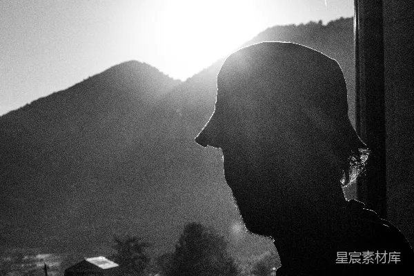 戴帽的男人望着日光中的山峦