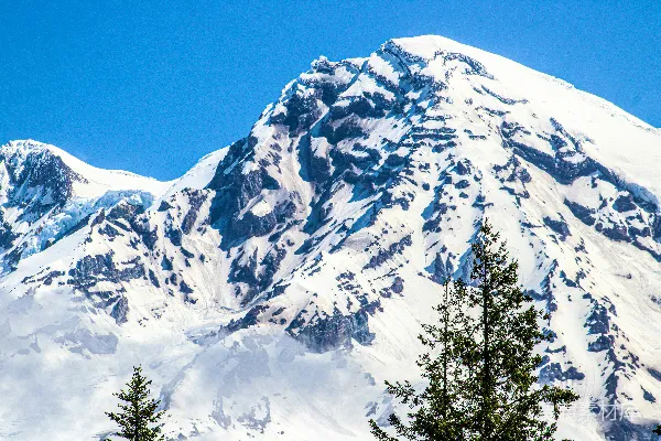 山脚下覆盖着白雪，树木环绕。