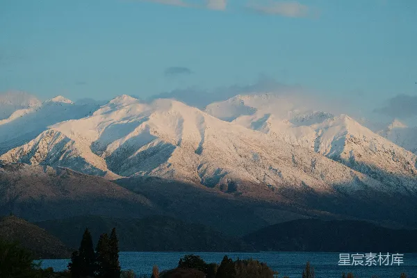 一幅覆盖着白雪的山峦远景中有一片湖泊。