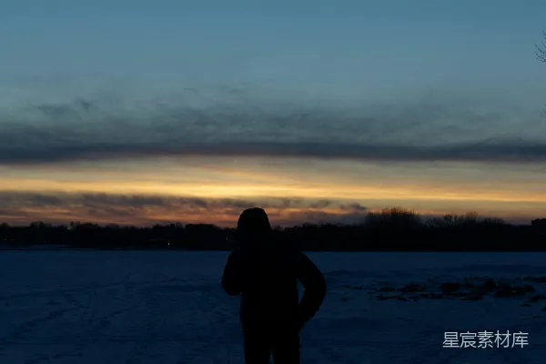雪地里站着的人在夕阳下。