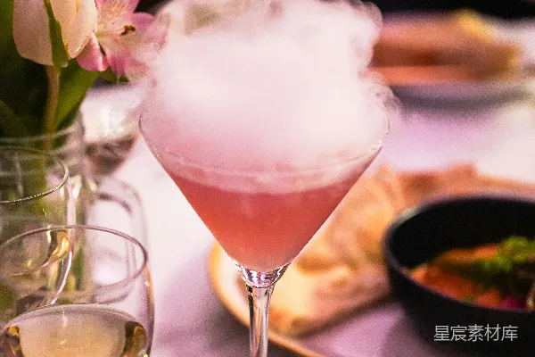 高清摄影 一杯粉色鸡尾酒，里面冒着烟，在马提尼酒杯中。