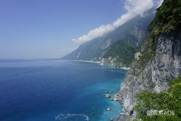 绿山蓝海间灰山白天映照蓝天之下