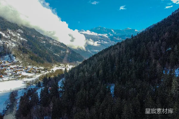 远处有一座被雪覆盖的山峦，旁边有一个小村庄。