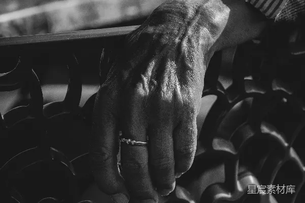 一位老人的手放在凳子上。