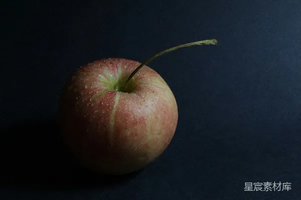 一只红苹果摆在黑色桌子的上面。