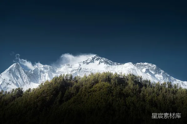 高清摄影 一座覆盖着雪和树木的山，蓝天白云下