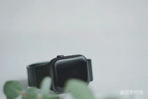 高清摄影 黑色智能手表旁边是绿叶植物