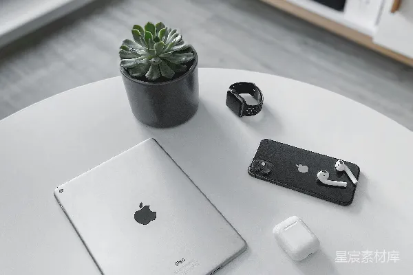 高清摄影 银色的MacBook放在白色桌子旁，旁边有一个白色的苹果魔法鼠标，桌子上还有一株绿色的植物。