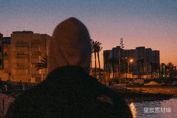 高清摄影 穿着黑色外套的男人站在水边，夕阳西下。