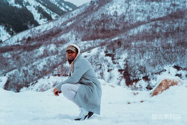 一个男子跪在雪前的山下