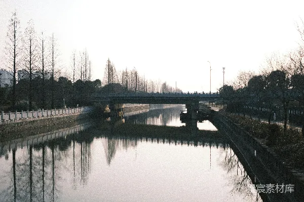 一座桥梁横跨着一条平静的河流，河面上映照着倒影。