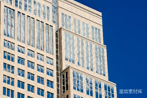 现代高层建筑，反射窗户在蓝色的天空下。