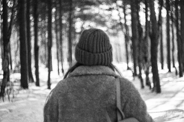 一个妇女穿过森林，手里拿着一块雪板。