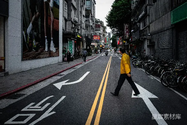 黄色夹克和黑色裤子的男人在白天走在人行道上