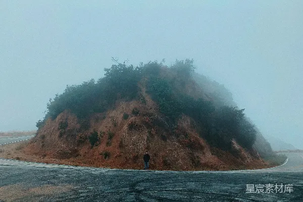 穿着黑色夹克的男人站在沥青路面上