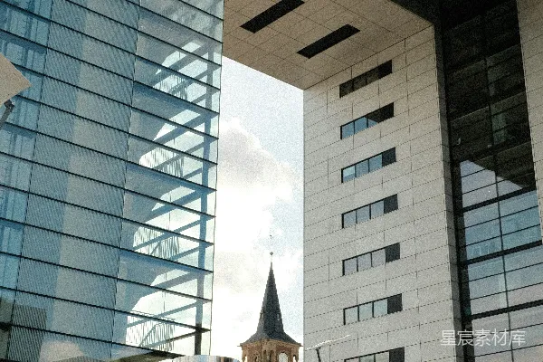 现代建筑环绕着一座教堂塔和圆柱形雕塑。
