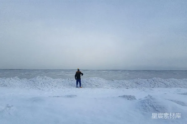 黑夹克的人在白天雪覆盖的田野上行走。