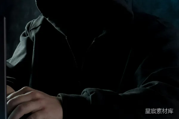 高清摄影 一个穿着连帽衫的男人在使用笔记本电脑。