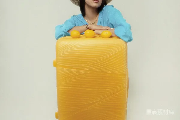 一个女子坐在一个黄色行李箱上
