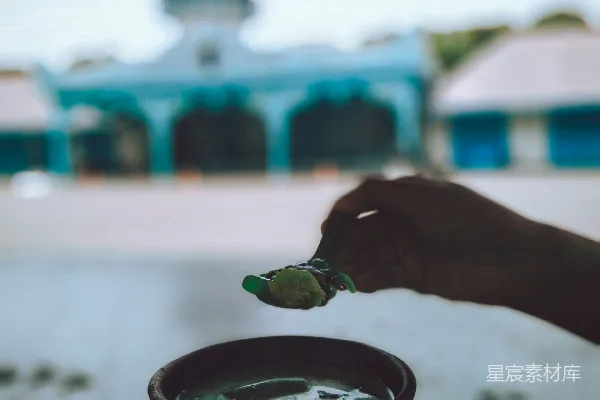 一只手拿着一碗汤，里面有一把勺子。
