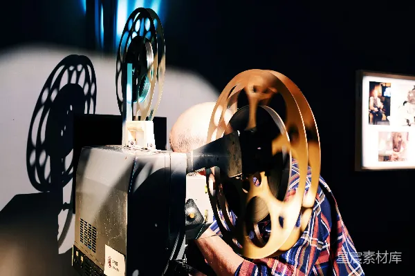 高清摄影 一个人正在操作一台带有金色胶卷的复古电影放映机。
